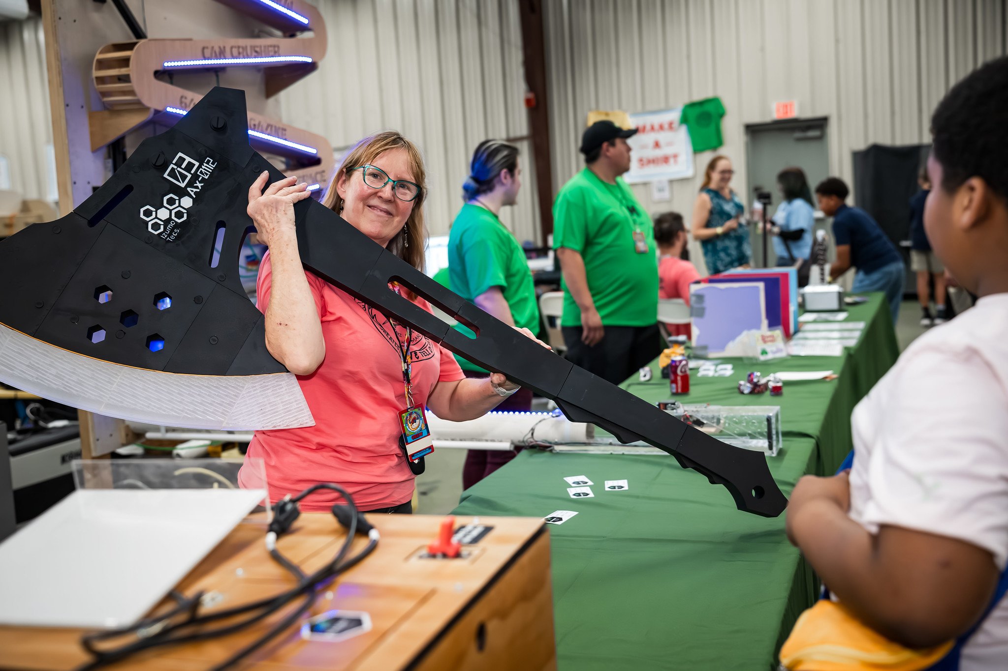 A crew member showing off a laser-cut prop axe at an exhibit table